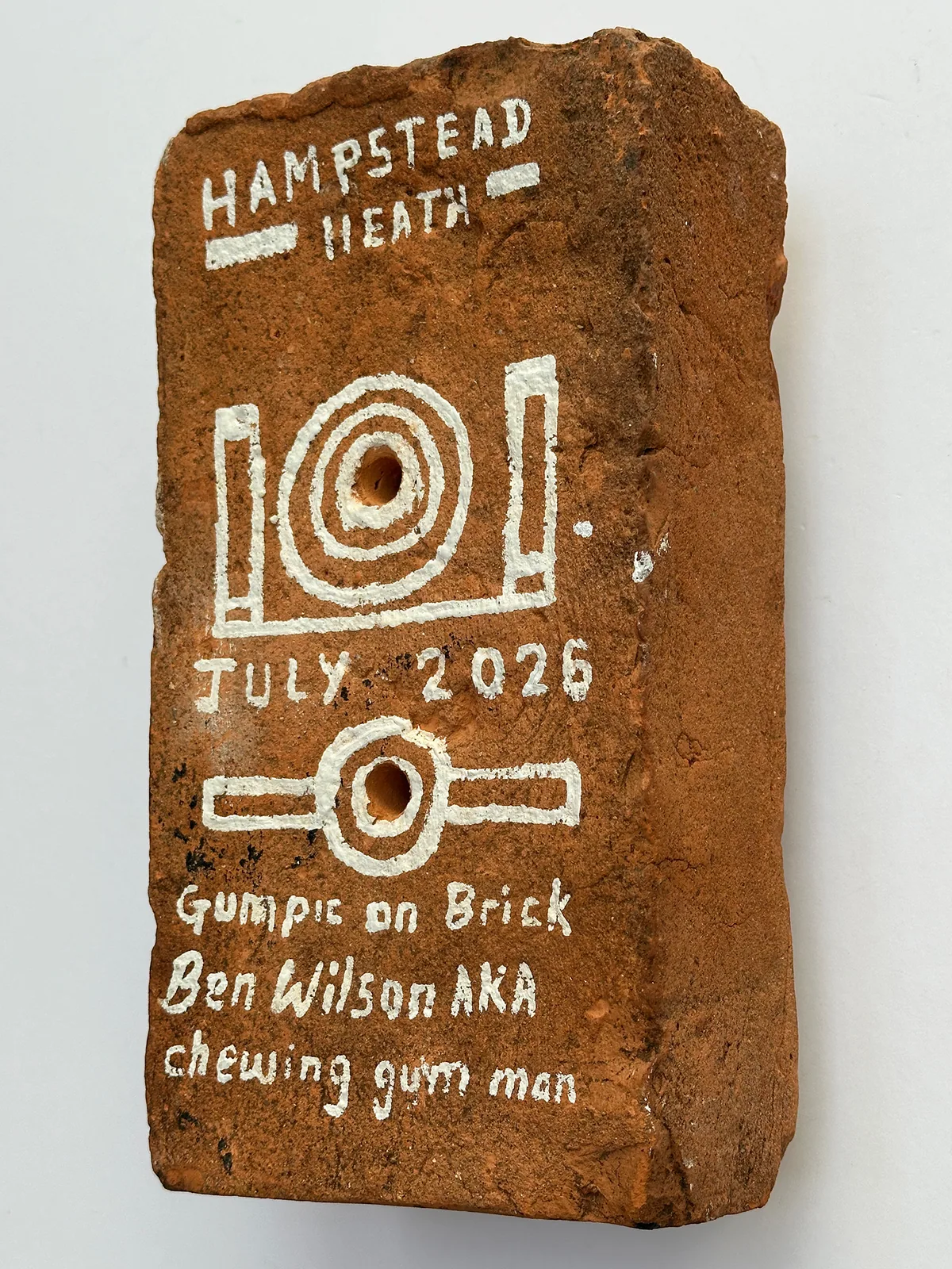 The back of the brick, painted with the words Hampstead Heath, July 2026, Gumpic on Brick, Ben Wilson AKA chewing gum man.
