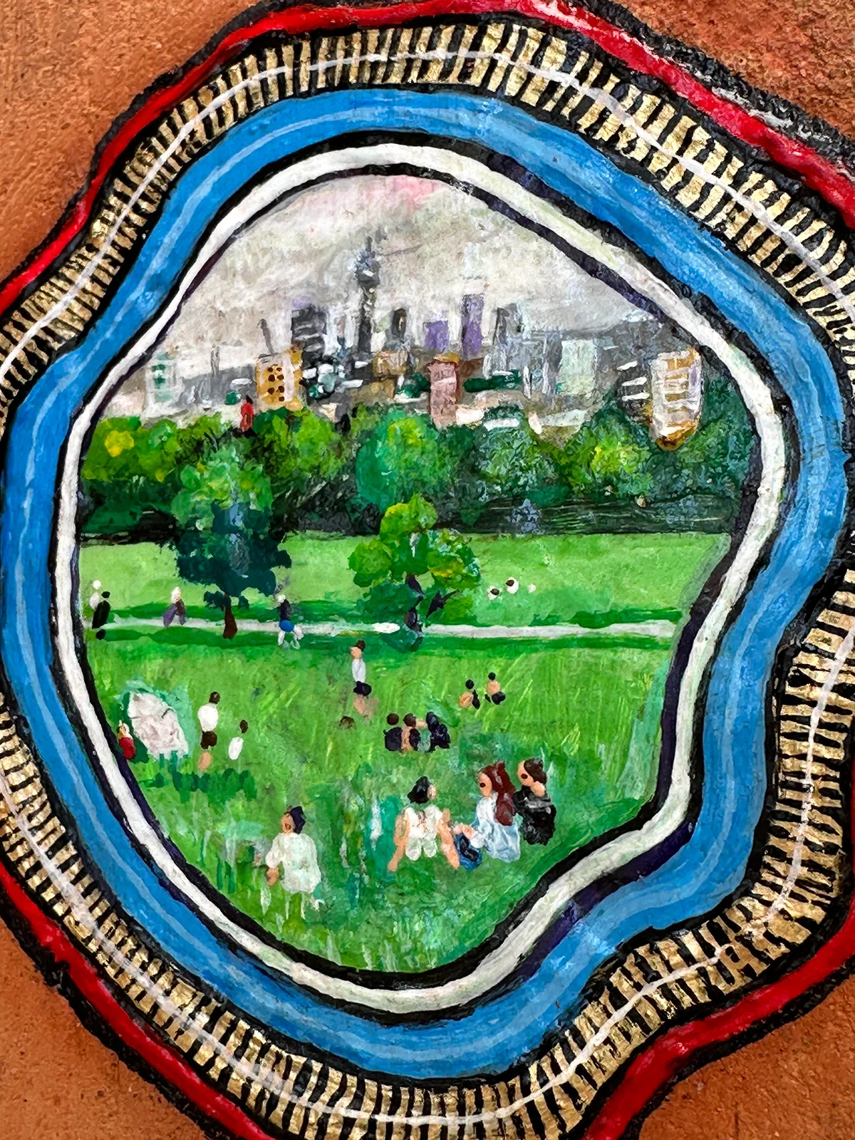 Close-up of the painted gum: people on the grass of Parliament Hill with the London skyline beyond.