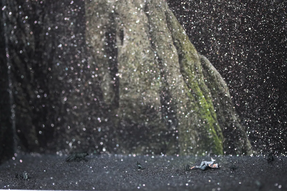 Detail: the tiny sleeping figure on the glittering forest floor beneath the great trunk.