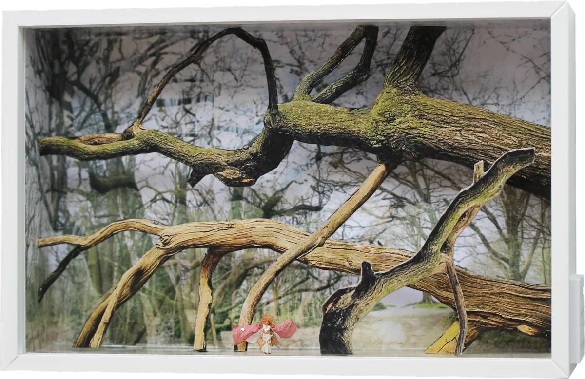 White box diorama of pale arching branches and bare trees, with a tiny winged figure in pink and white.